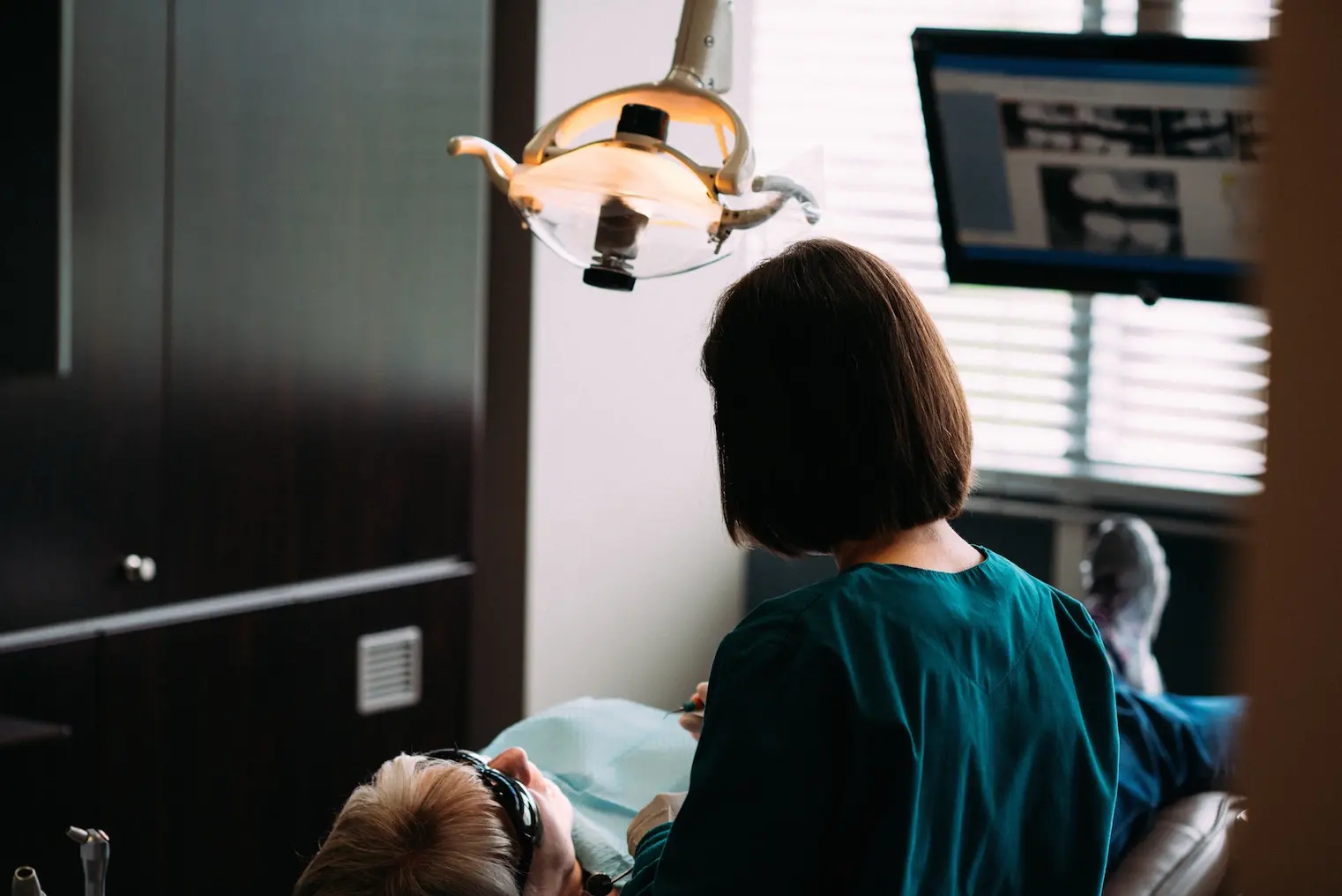 Senior patient receiving dental examination under overhead light at Eugene dental office.